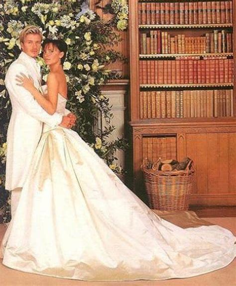 A Bride And Groom Posing For A Wedding Photo In Front Of A Bookshelf