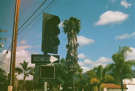 A Traffic Light Sitting On The Side Of A Road Under A Blue Sky With Clouds