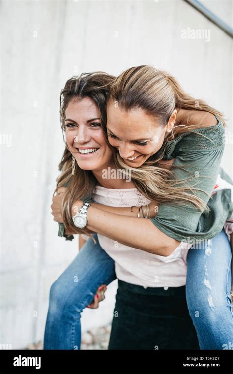 Portrait Of Laughing Woman Giving Her Friend A Piggyback Ride Stock