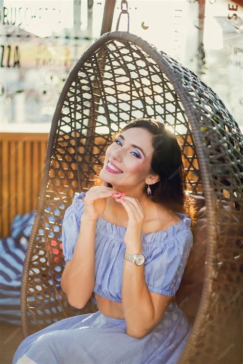 Premium Photo A Beautiful Young Woman Is Sitting In A Wicker Hanging