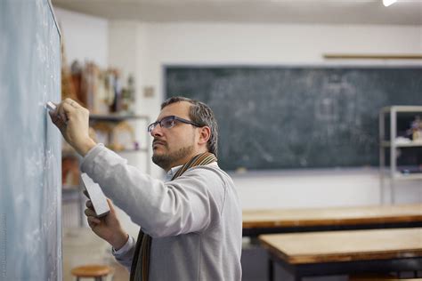 Professor Writing At The Blackboard Of The Classroom Del Colaborador