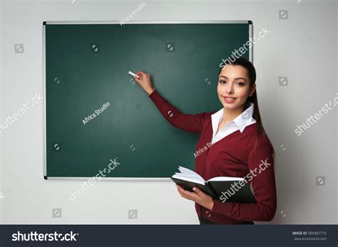 Beautiful Young Teacher Writing On Blackboard Stock Photo 589387775