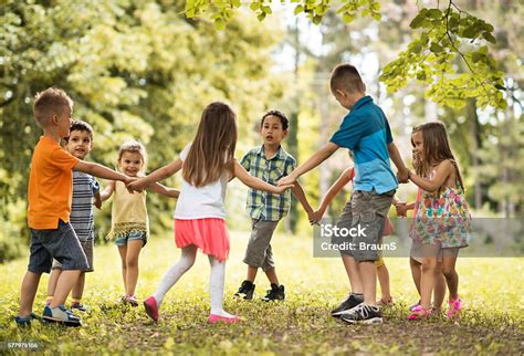 Group Of Small Kids Playing Ringaroundtherosy In The Park Stock Photo