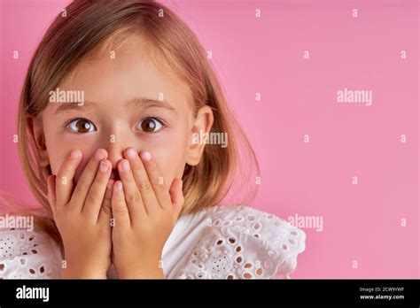 Portrait Of Little Caucasian Girl In Shock She Is Surprised By Something Hold Hands On Mouth