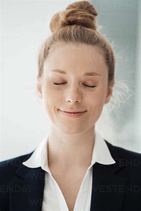 Smiling Businesswoman With Eyes Closed At Office Stock Photo
