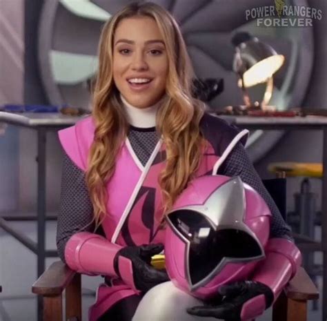 A Woman Sitting In A Chair Wearing A Pink Suit And Holding A Motorcycle Helmet On Her Lap