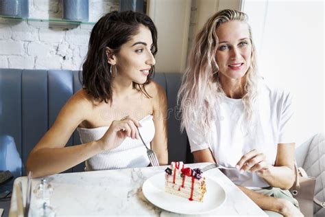 Two Laughing Girlfriends Are Eating Dessert In A Cafe The Joy Of