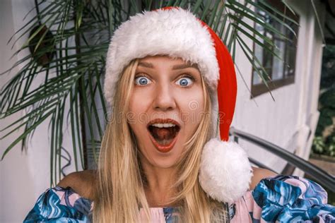 Funny Shocked Blonde Woman Wearing Santa Hat Looking Into Camera With