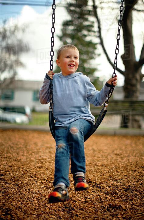 Young Boy Playing On A Swing In A Park Stock Photo Dissolve