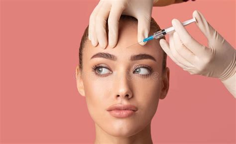 Young Woman Receiving Botox Beauty Injection In Forehead Studio Shot