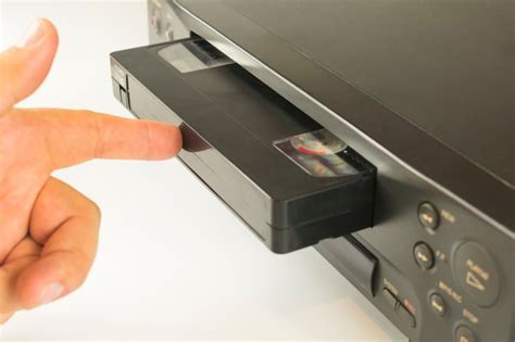 Premium Photo Finger Pushing A Video Cassette Into The Inside Of A