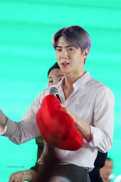 A Man Holding A Red Heart Shaped Pillow While Standing Next To A Woman In A White Shirt