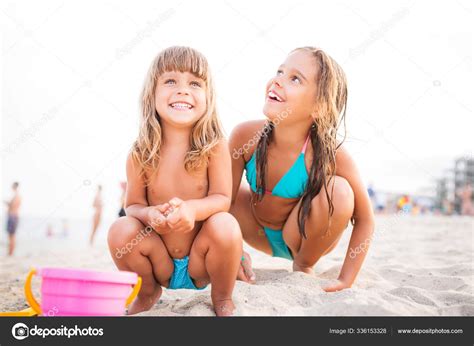 Deux filles jouent sur la plage tout en étant assis dans le sable image