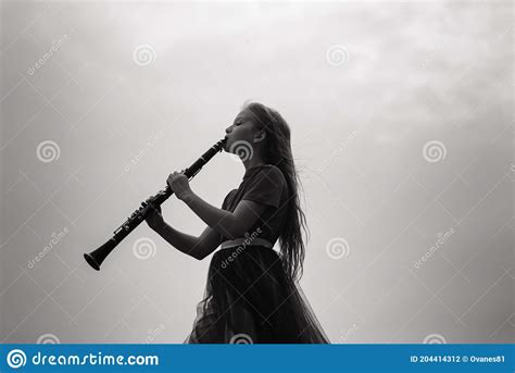 Young Attractive Girl Playing Clarinet Ebony In Fall Park Stock Photo