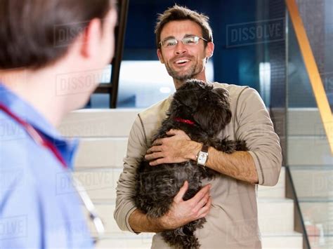 Man Holding Dog At Vet Stock Photo Dissolve