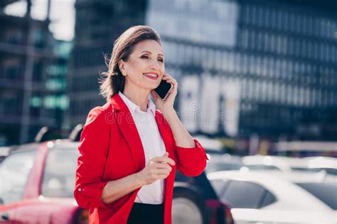 Photo Of Adorable Cheerful Mature Lady Wear Red Jacket Walking Talking Modern Device Outside