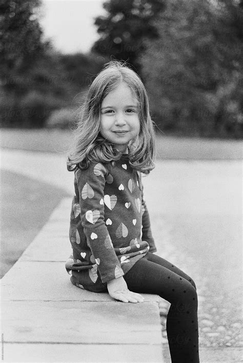 Black And White Portrait Of A Beautiful Young Girl Sitting On A Stone