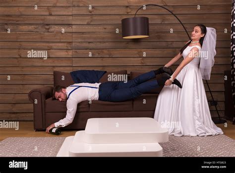 Bride Is Trying To Wake Up A Drunk Sleeping On Couch Groom After Wedding Celebration Wooden