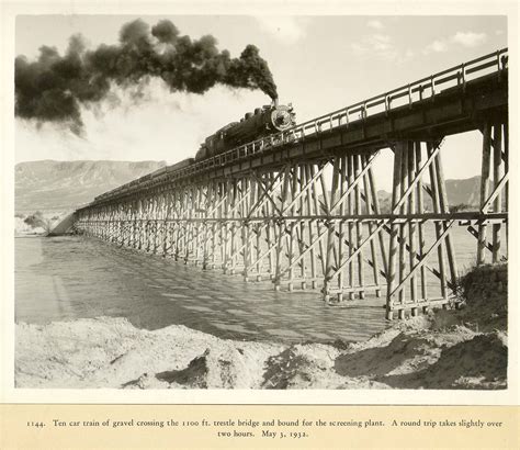 Railroad Freight Cars Carrying Gravel Across A Trestle Bridge On The