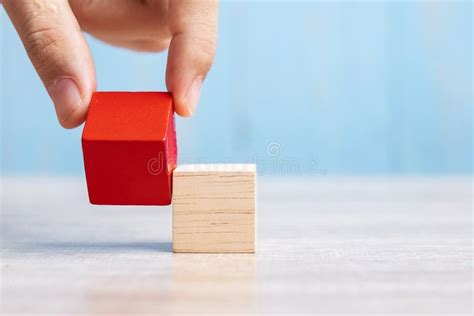 Businessman Hand Placing Or Pulling Red Wooden Block On The Building