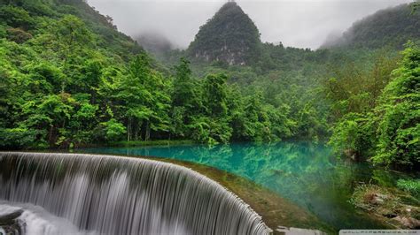 Green Trees Near Lake With Reflection And Waterfall In Fog Forest