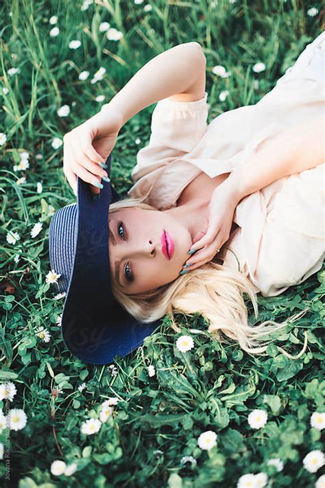 Beautiful Young Woman Lying On Grass Wearing A Summer Hat By Jovana Rikalo Stocksy United
