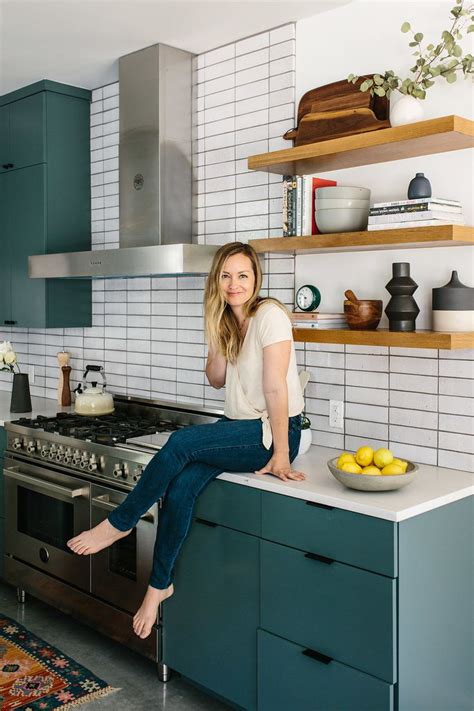 A Woman Sitting On Top Of A Counter In A Kitchen