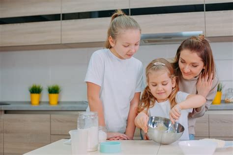 Premium Photo Mom Teaches Her Daughters To Cook Dough In The Kitchen