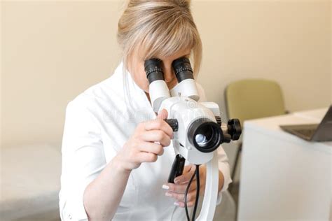 Female Blond Doctor Gynecologist Looks Through A Colposcope