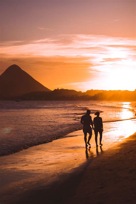 Silhouette Of Two People Walking On Beach During Sunset · Free Stock Photo