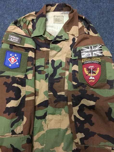 A Camouflage Jacket With Patches On The Chest And Two Badges On The
