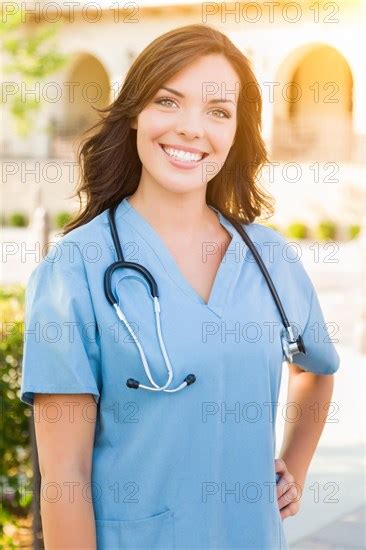 Portrait Of Young Adult Female Doctor Or Nurse Wearing Scrubs And