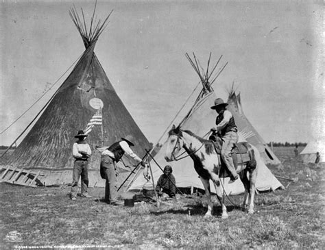 An Old Black And White Photo Of People On Horses In Front Of Teepees