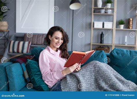Happy Young Woman Relaxing Reading Sit On Sofa At Home Stock Photo