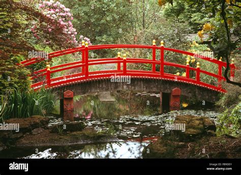 Red Japanese Style Bridge Over Stream In Woodland In A Large Country