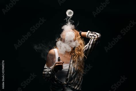 Redhead Woman Vaping Electronic Cigarette With Smoke On Black