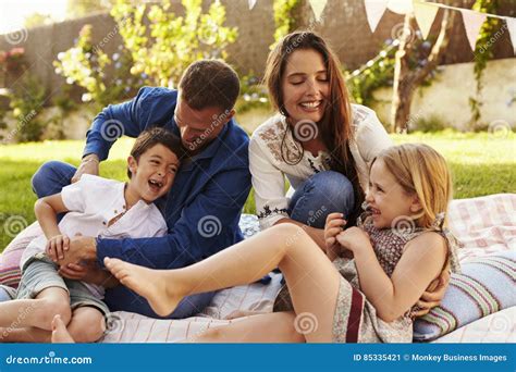 Parents Playing Game With Children On Blanket In Garden Stock Image