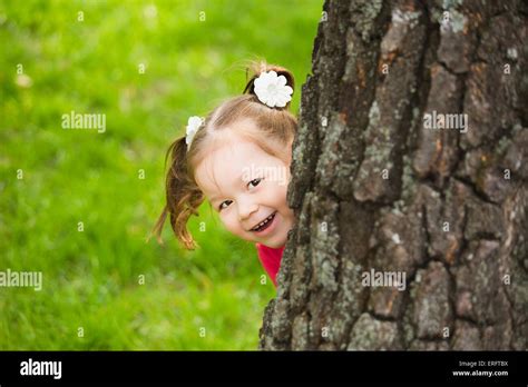 cute little girl hiding behind huge tree. kids portrait looking at ...