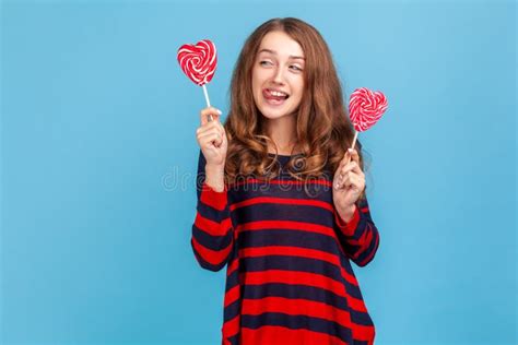 funny hungry woman showing tongue out wants to taste heart shape candy in her hands stock