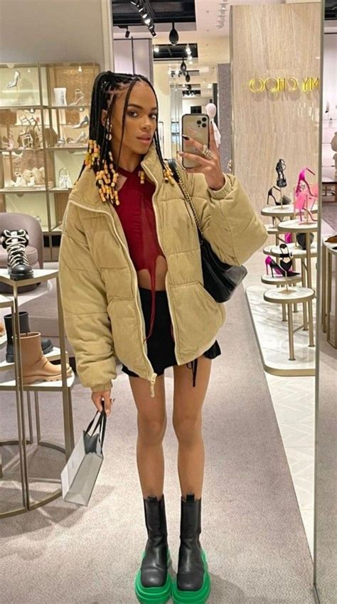 A Woman Taking A Selfie With Her Cell Phone In A Clothing Store While Wearing Black Boots