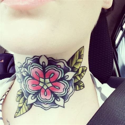 A Woman With A Flower Tattoo On Her Neck