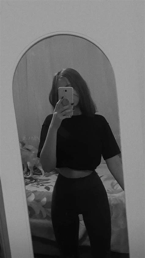 A Woman Taking A Selfie In Front Of A Mirror Wearing Black Pants And Crop Top