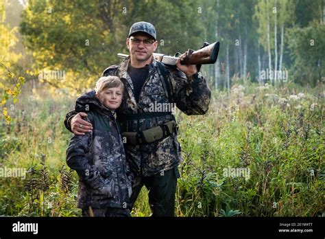 Father And Son Standing Together Outdoors With Shotgun Hunting Gear
