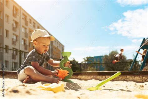 Child Playing In Sandbox Little Boy Having Fun On Playground In