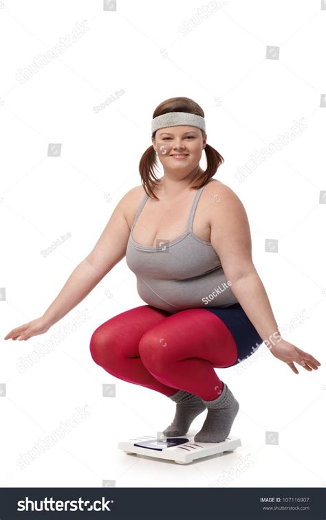 Fat Woman Squatting On Scale Smiling Happily Stock Photo