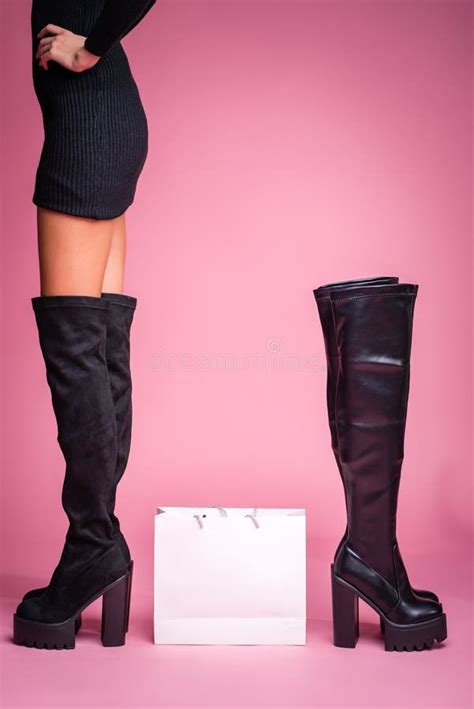 The Girl Stands In Black Jackboots On Her Feet On A Pink Background In The Middle There Is A