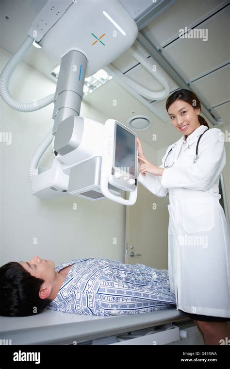 A Patient Lying On A Bed And A Doctor Using X Ray Machine Stock Photo