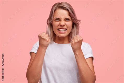Angry Young Woman Demonstrates Her Aggression Keeps Fists And Clenches Teeth Looks Furiously