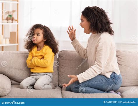 Angry Mother Shouting At Daughter Sitting On Couch At Home Stock Image