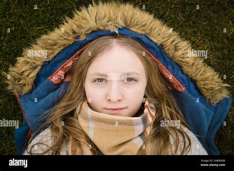 Portrait Of Beautiful Young Woman With Blonde Hair And Blue Eyes Lying Down On Ground Stock
